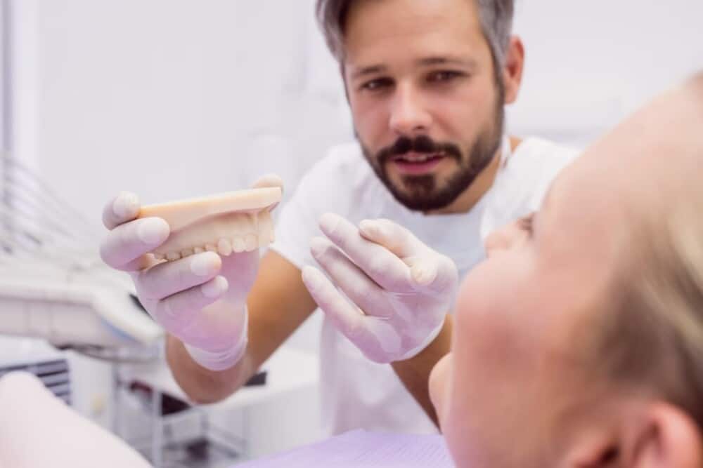 dentista mostrando modelo prótesis dentales paciente