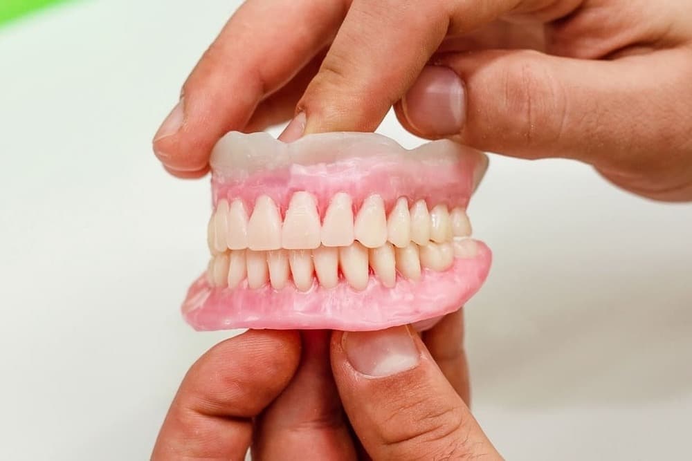 dentista sujetando dentadura artificial removible