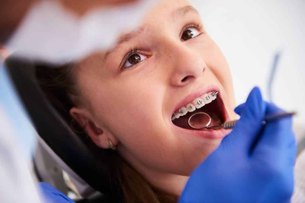 niña en consulta dental con brackets recibiendo revision