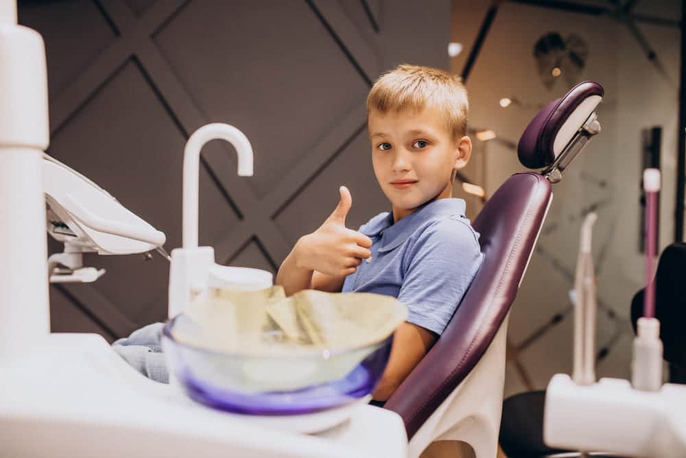 niño en dentista levantando pulgar tras consulta